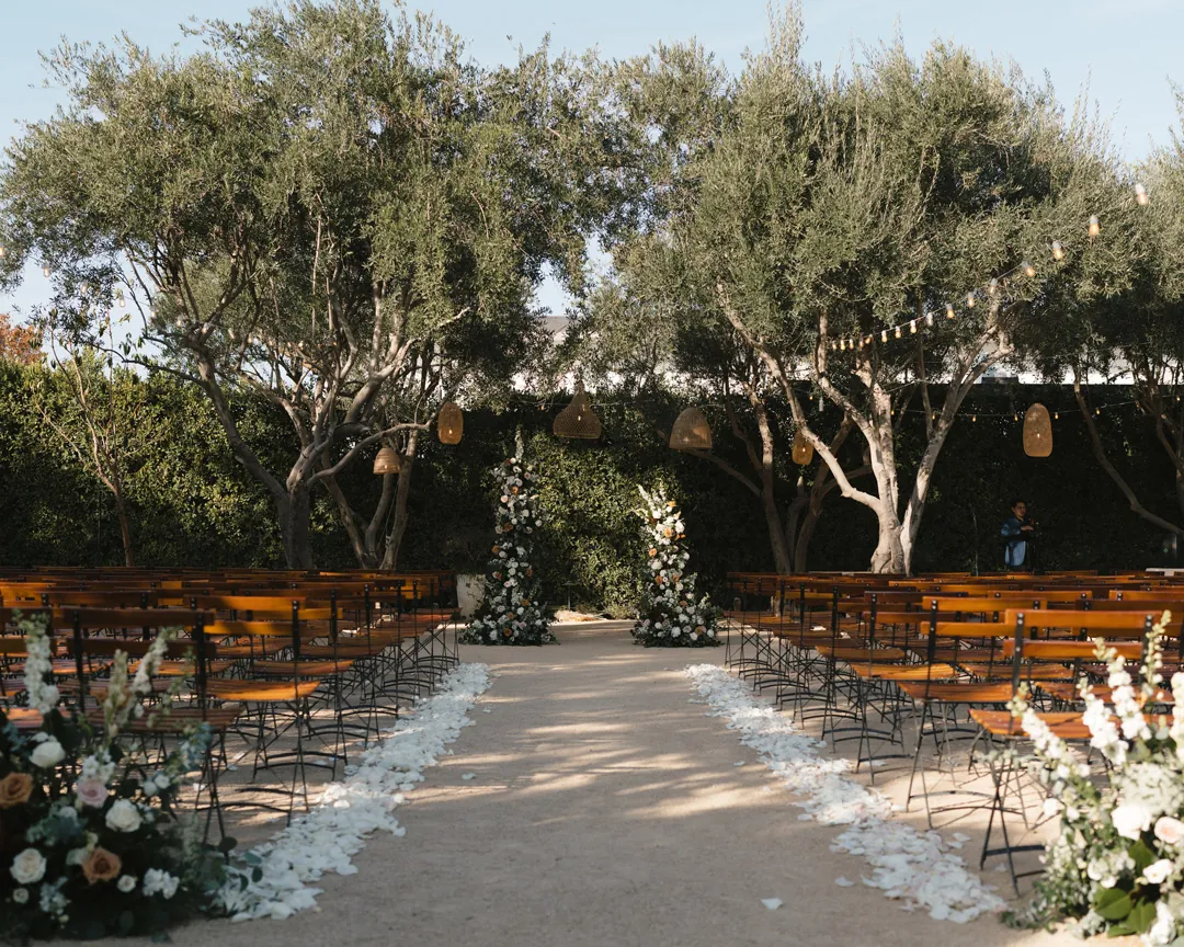 White petals and flowers line the olive-grove ceremony aisle.