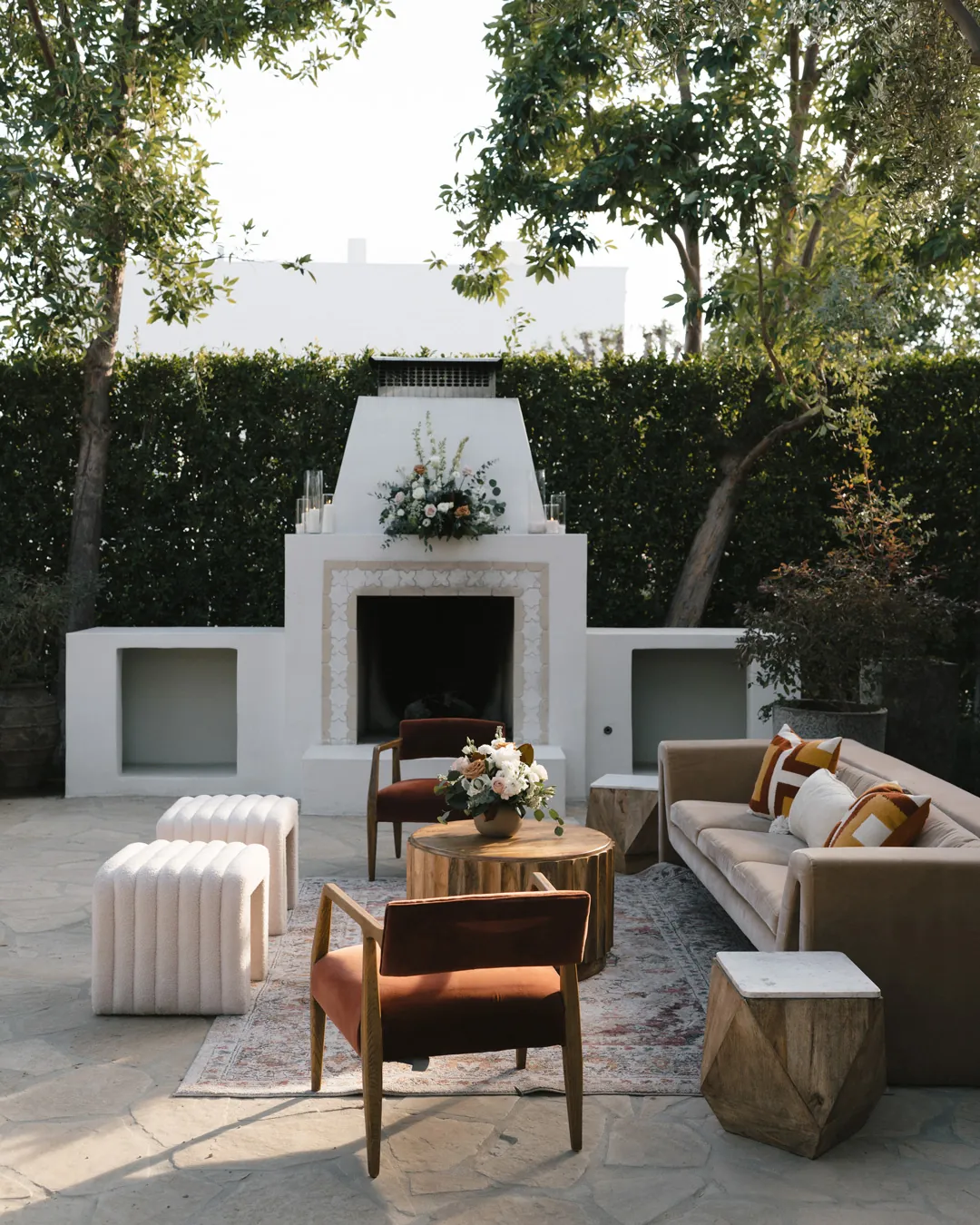 Wooden lounge chairs and white cushions face the courtyard fireplace.
