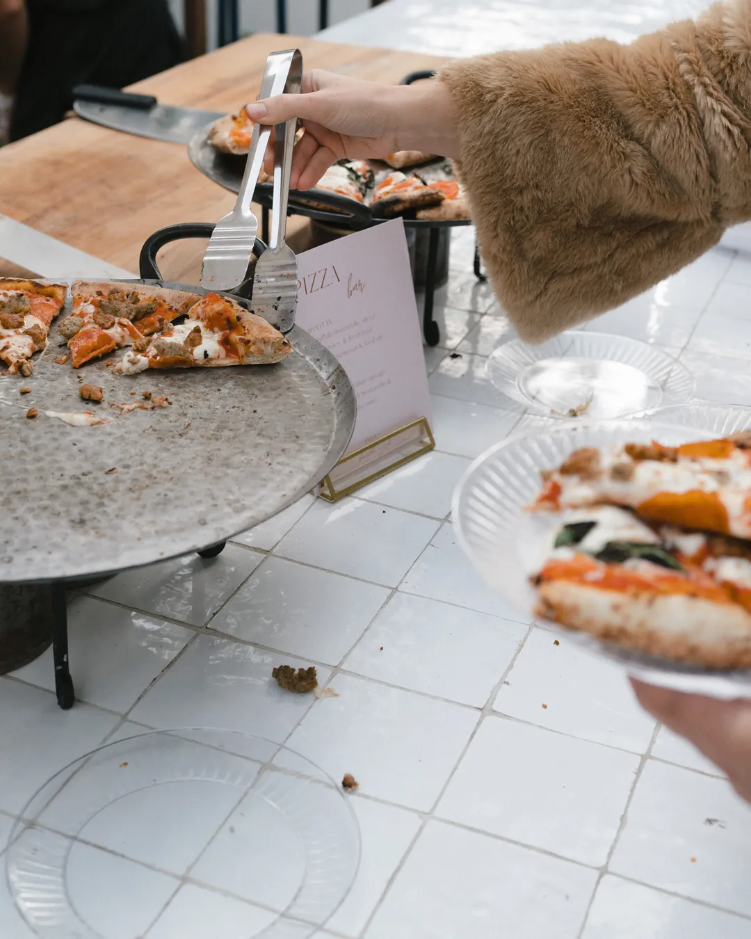 Guest serving pizza from a reception food station.