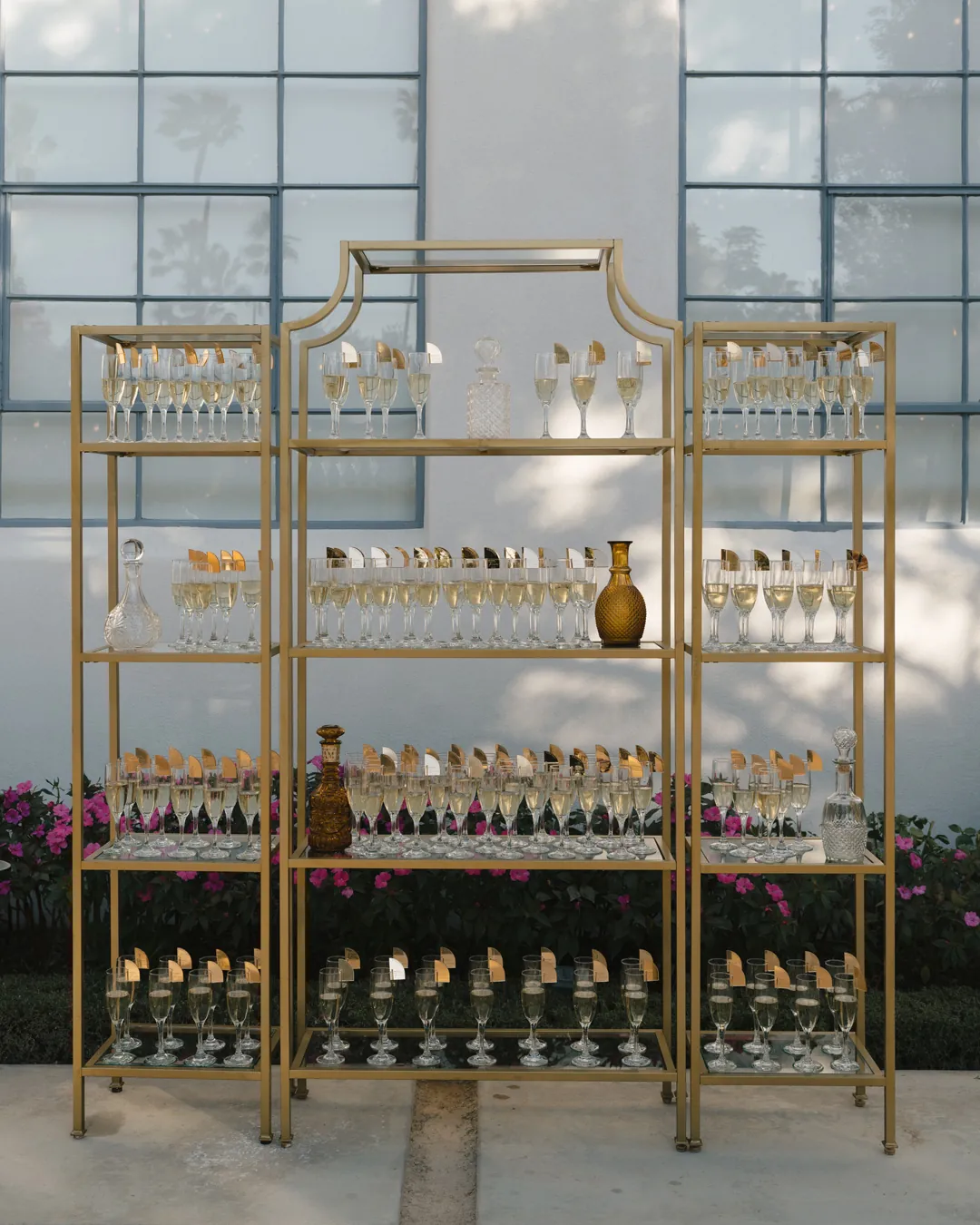 Gold display shelving stocked with bottles and glassware.