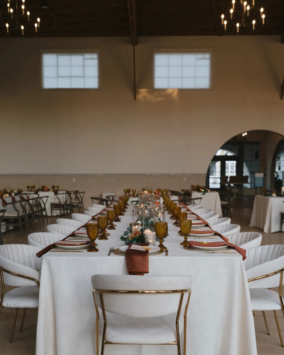 Long indoor reception table decorated with white linens and flowers.