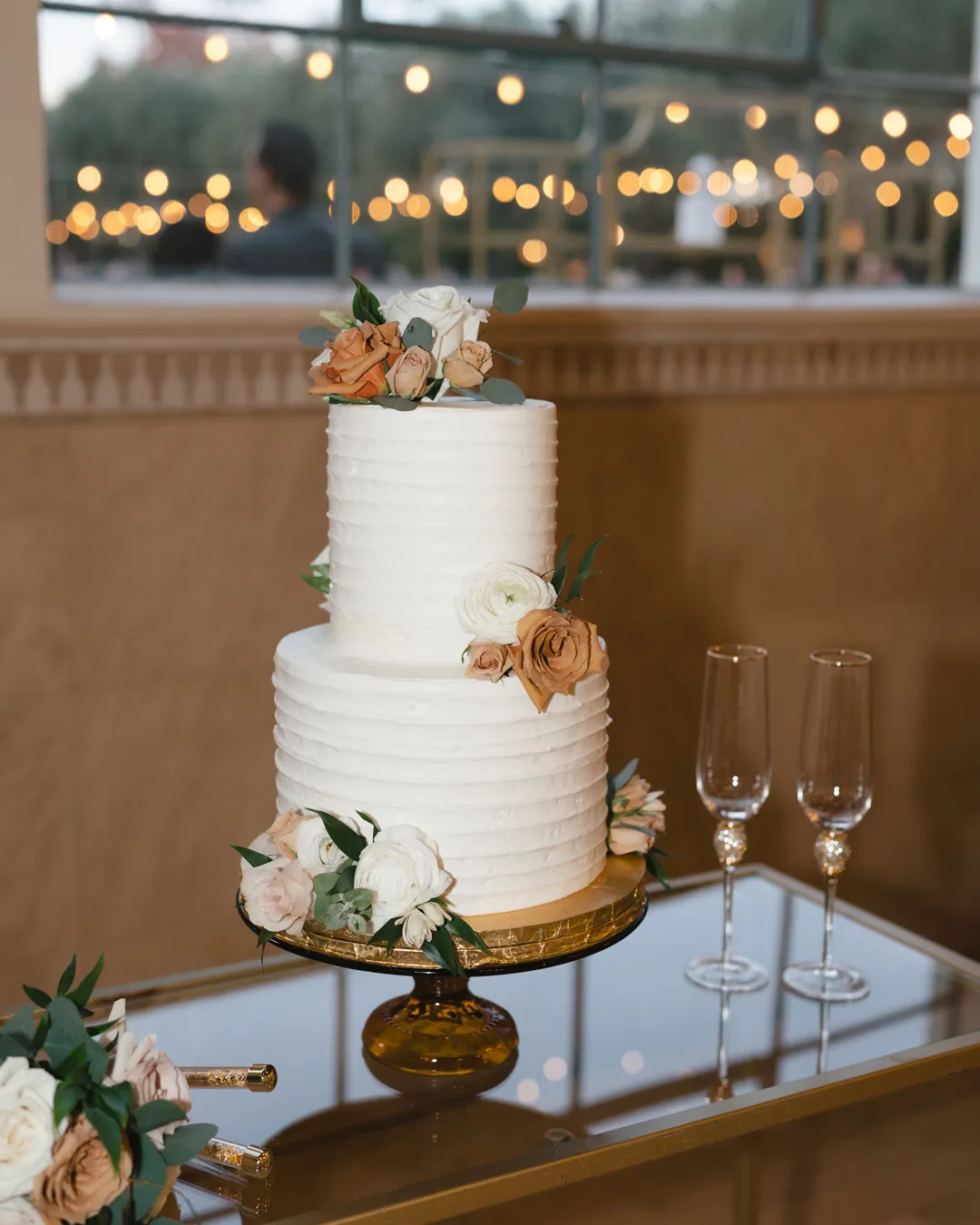 Two-tier wedding cake decorated with peach flowers.