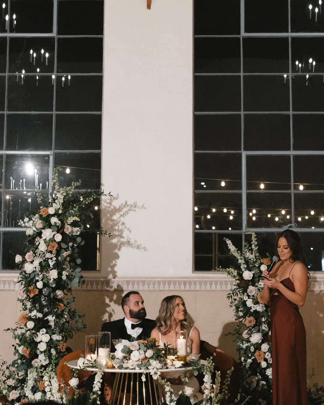 Guest giving a microphone toast beside the sweetheart table.