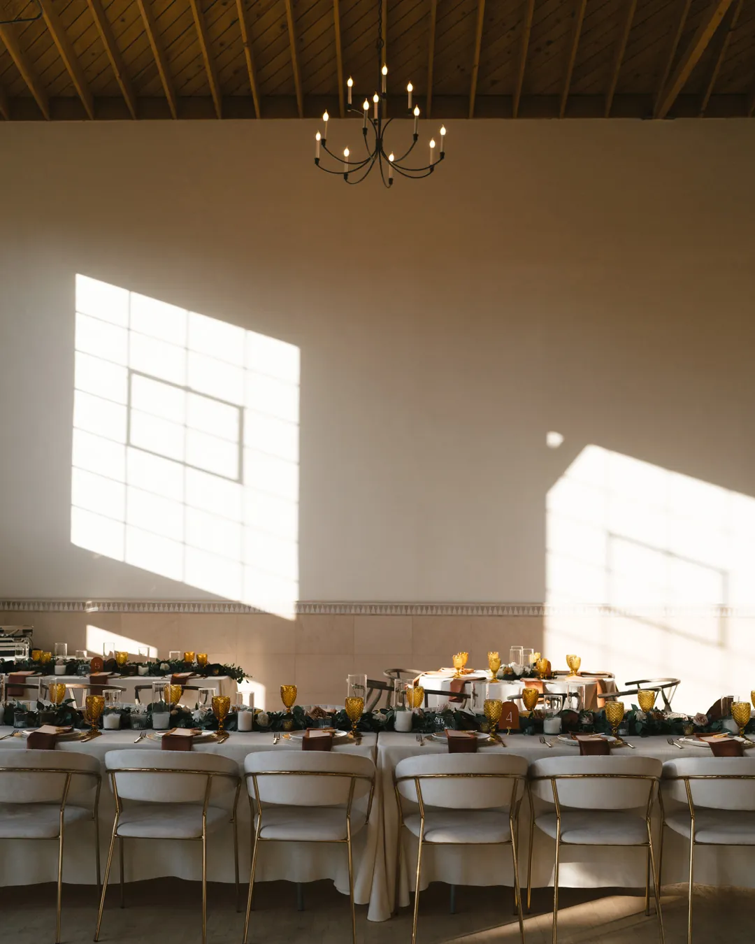 Sunlight falling across indoor reception tables and a wooden ceiling.