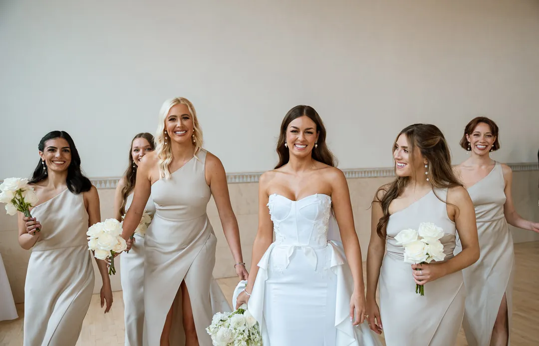 Bride posing with bridesmaids in pale dresses
