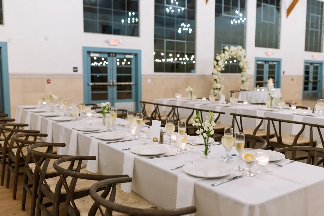 Long reception tables with white plates and candles