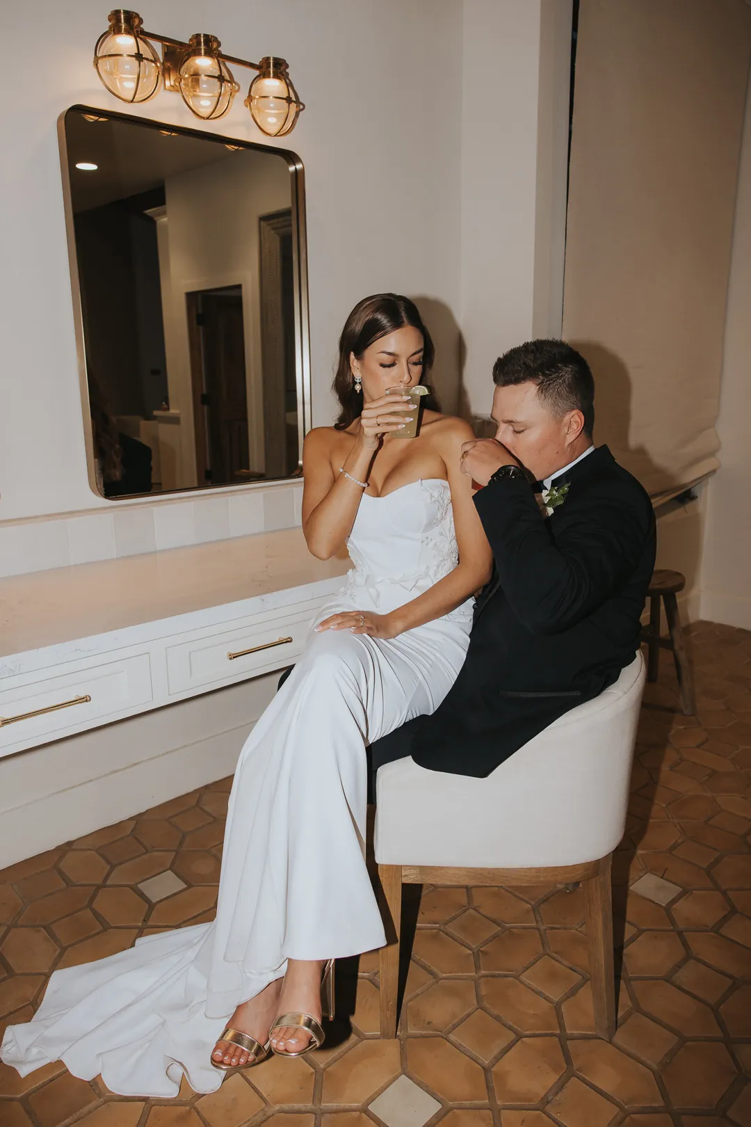 Bride and groom seated beside a dressing-room mirror