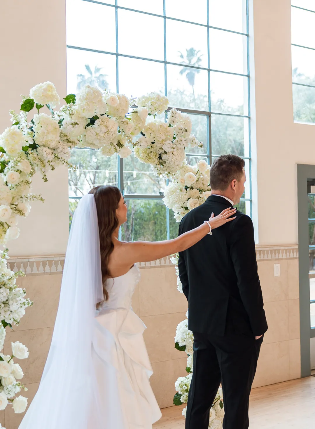 Bride approaching the groom beneath a floral arch
