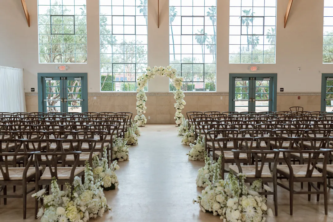 Indoor ceremony aisle facing a white floral arch