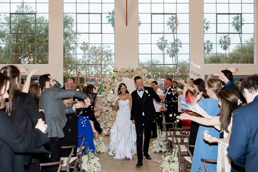 Bride and groom walking between cheering wedding guests