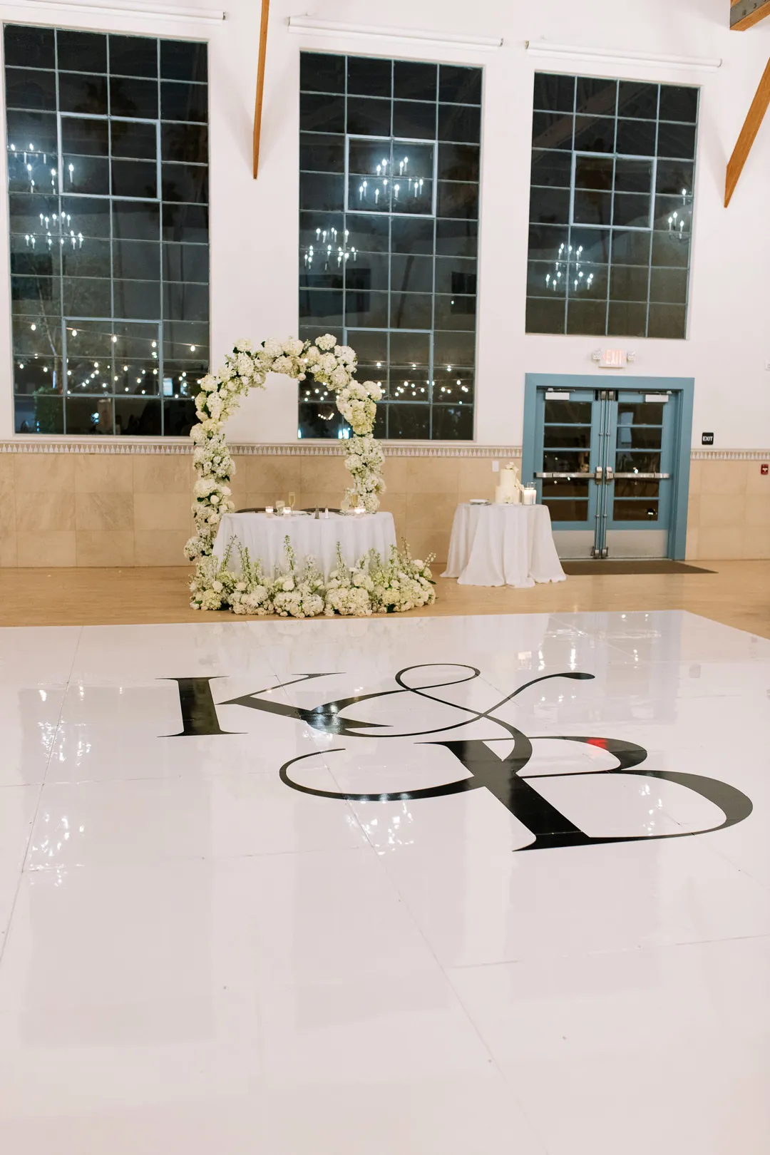 White dance floor beside a flower-framed sweetheart table
