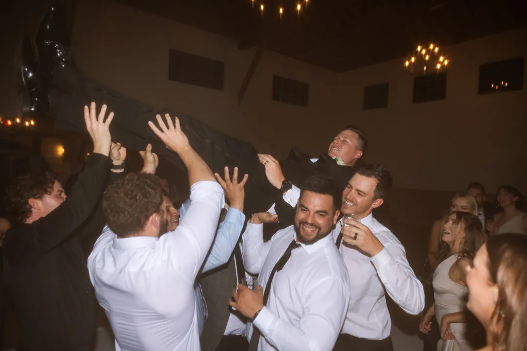Wedding guests dancing together inside the reception hall