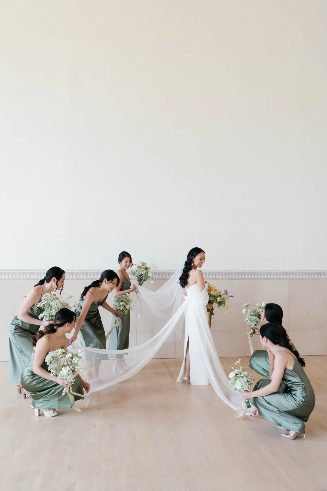 Bridesmaids arranging the bride’s veil and train