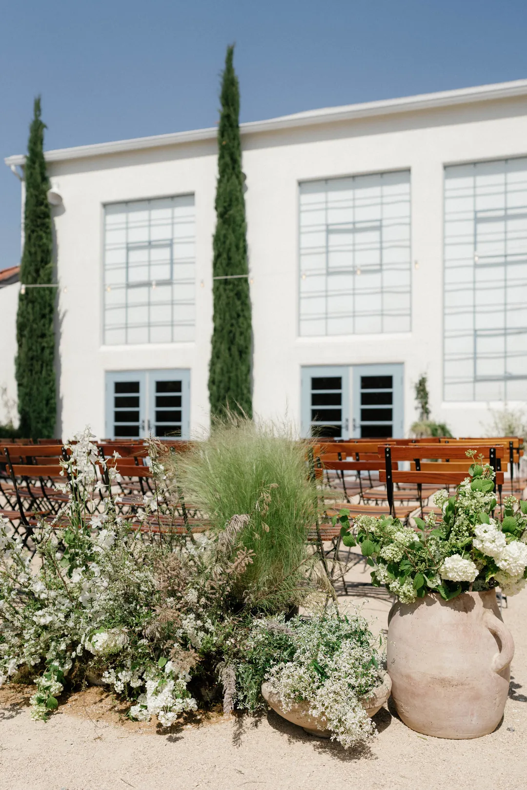 Low white floral arrangements outside the tall reception hall windows