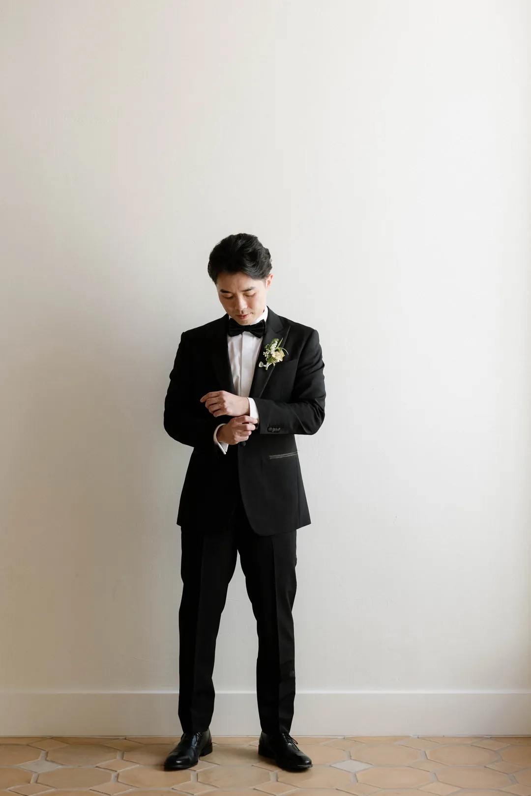 Groom looking down while fastening his cuffs