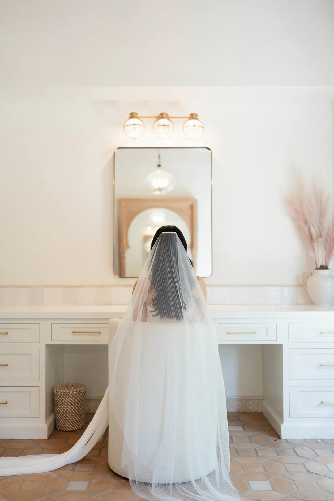 Veiled bride standing before a dressing-room mirror