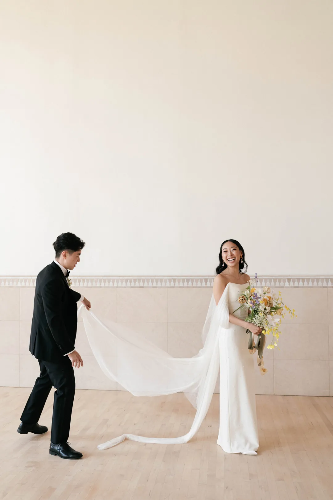 Groom holding the edge of the bride’s veil