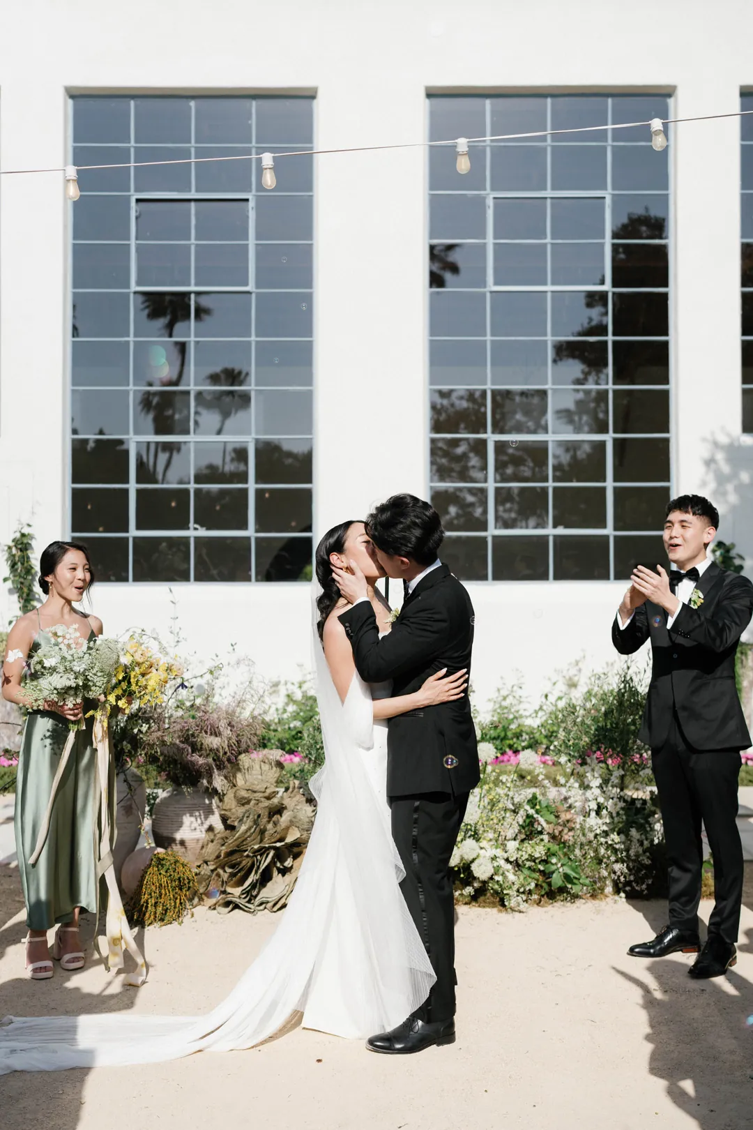 Bride and groom kissing outside the tall reception hall windows
