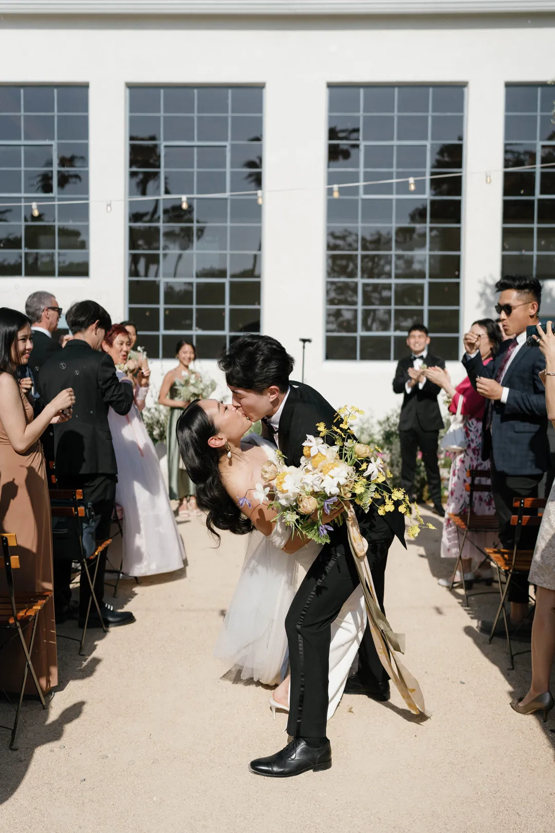 Groom bending forward beside the bride in the ceremony aisle