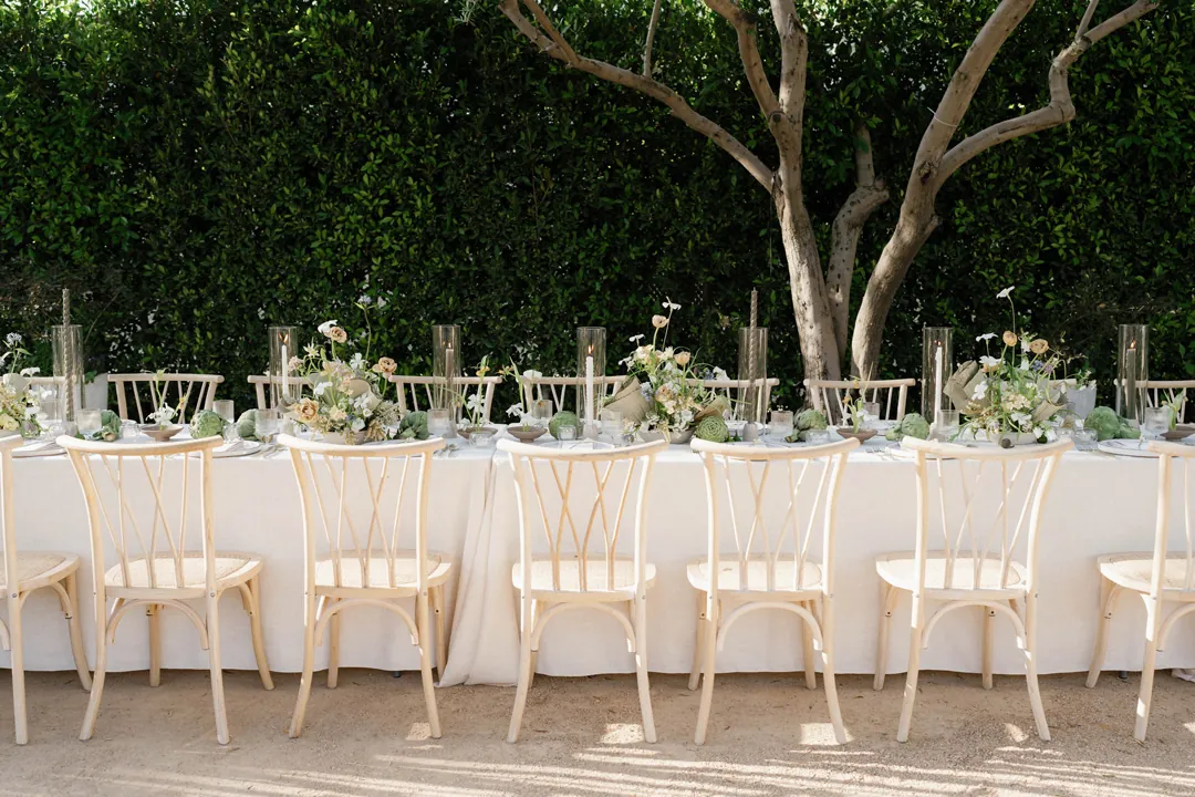 Long courtyard table set with white linens and flowers