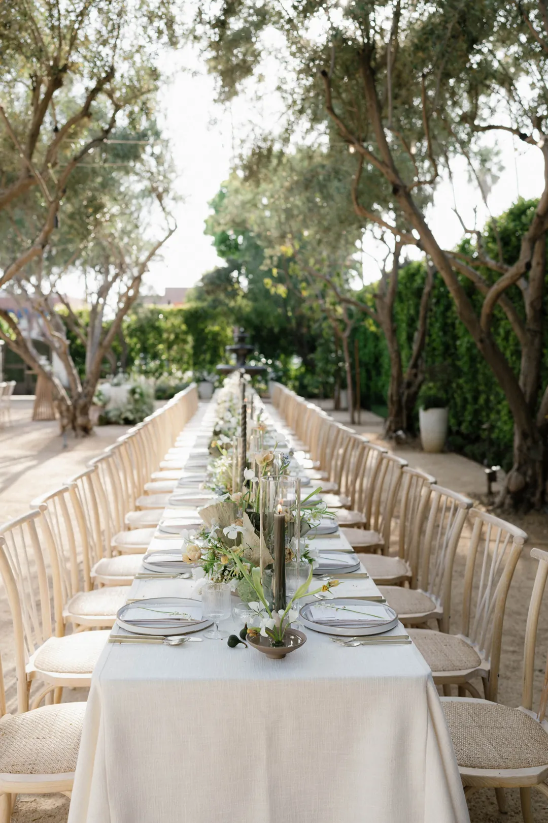 Long white dining table with flowers and slender candles