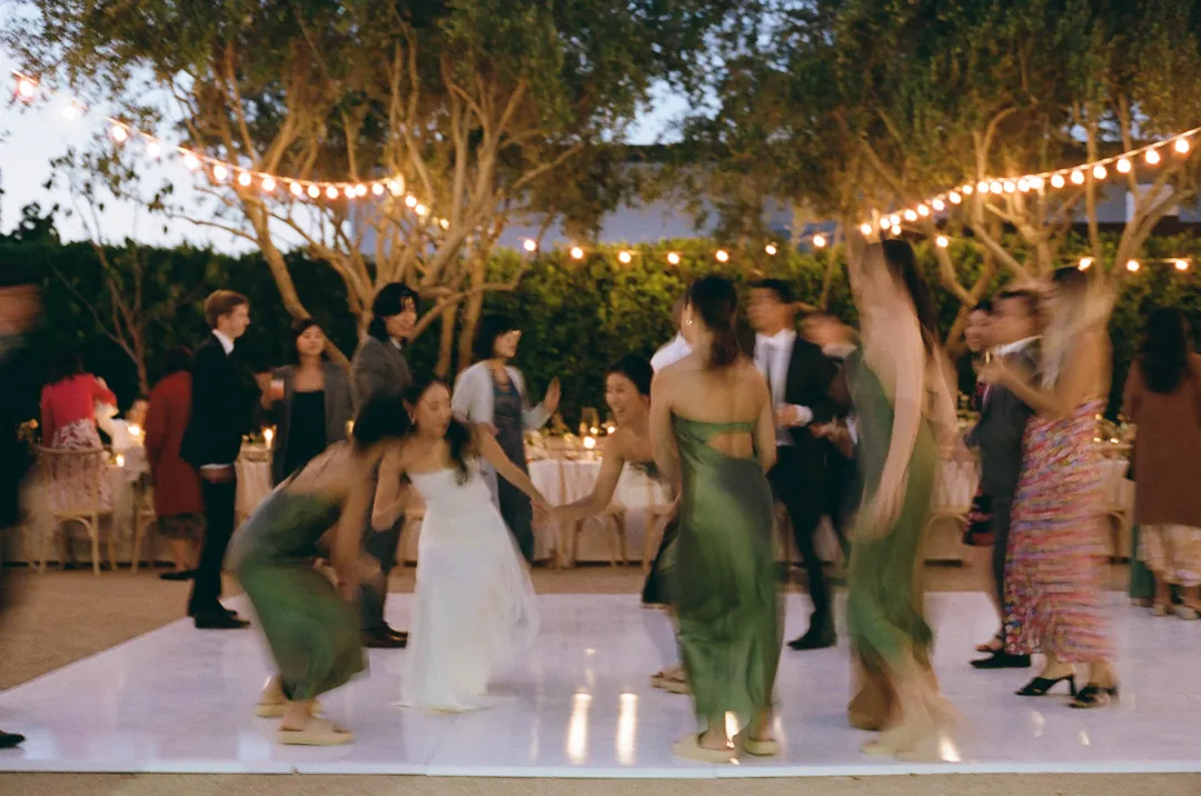 Wedding guests dancing beneath courtyard string lights