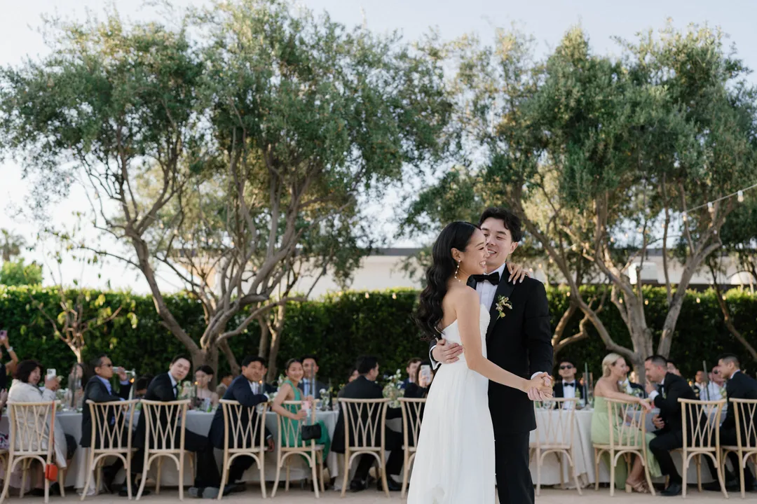 Bride and groom dancing in front of outdoor dining guests