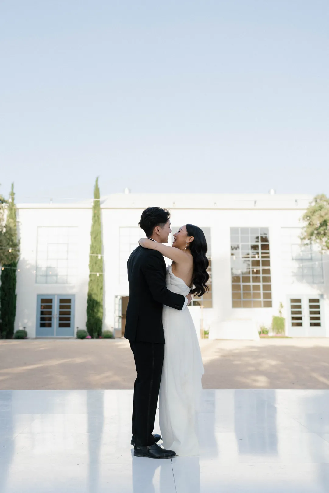 Bride and groom kissing on a white dance floor