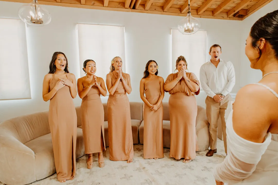 Bridesmaids smiling as they see the bride’s dress