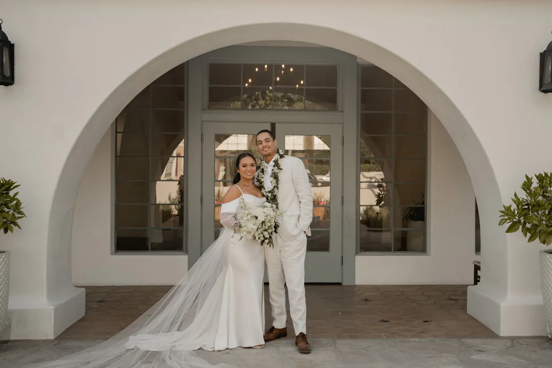 Bride and groom beneath the arched venue entrance