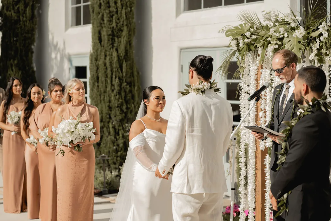 Officiant addressing the bride and groom beneath hanging flowers