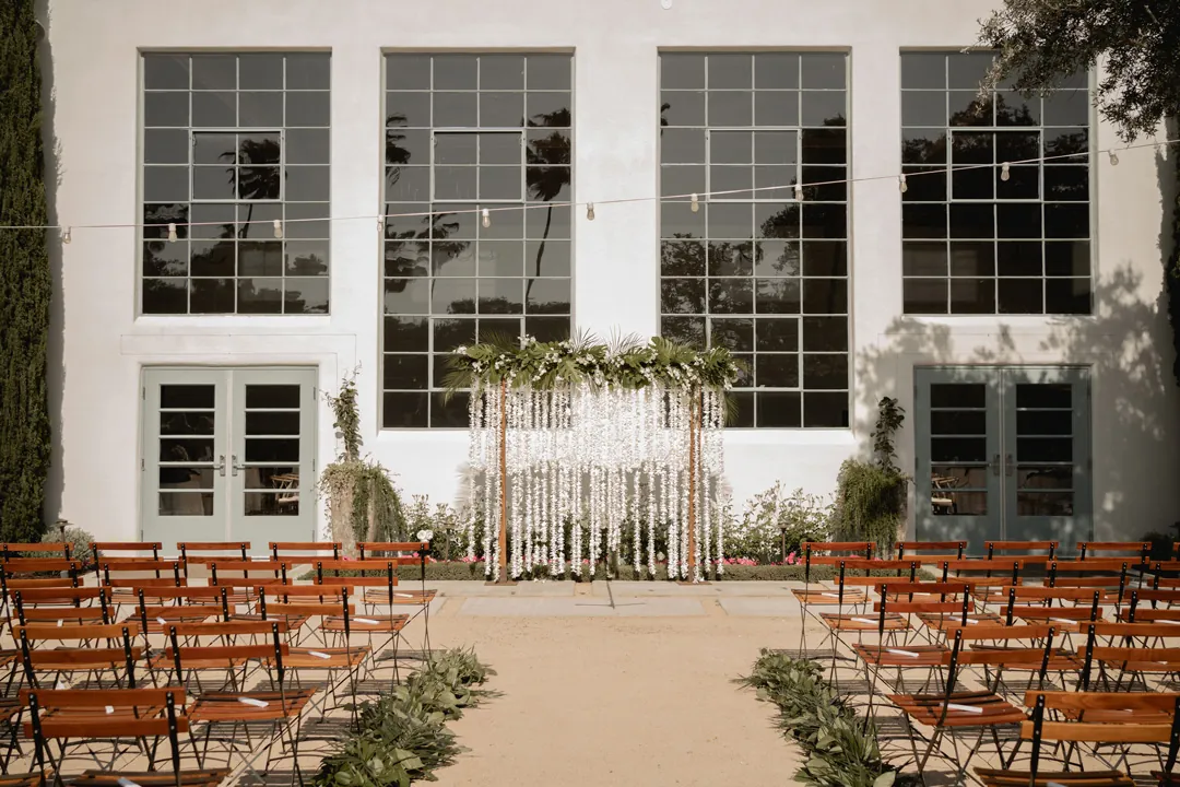 Courtyard ceremony chairs facing a white floral backdrop