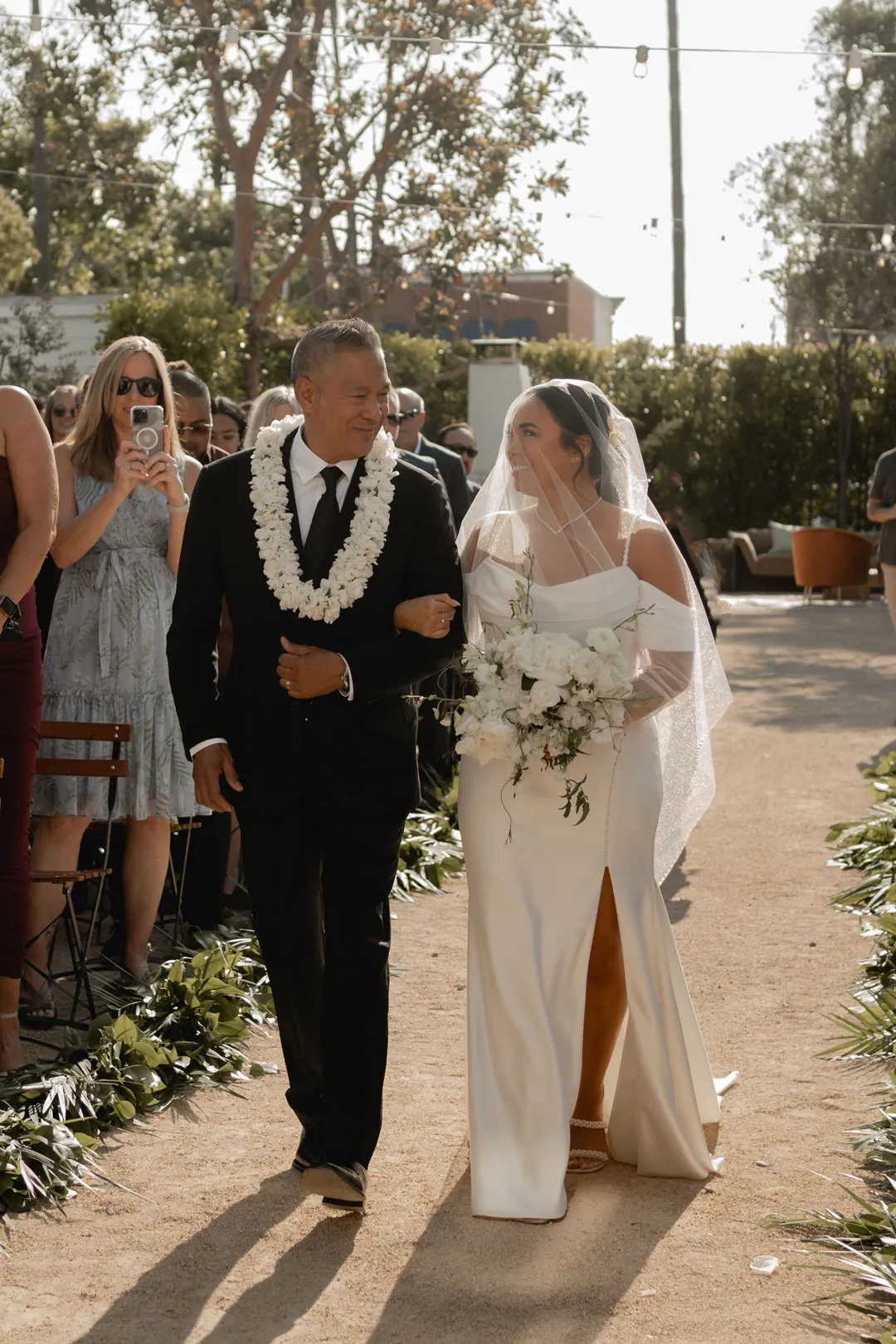 Bride and escort walking between seated wedding guests