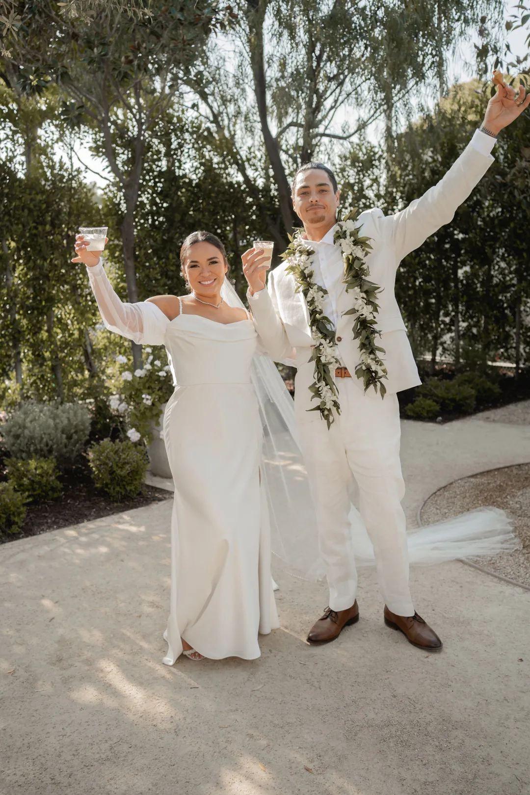 Bride and groom raising their arms in the courtyard