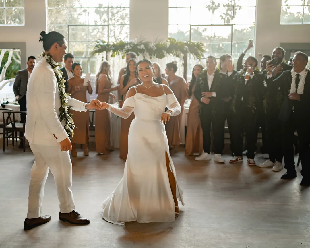 The couple dances together while guests watch in the reception hall.