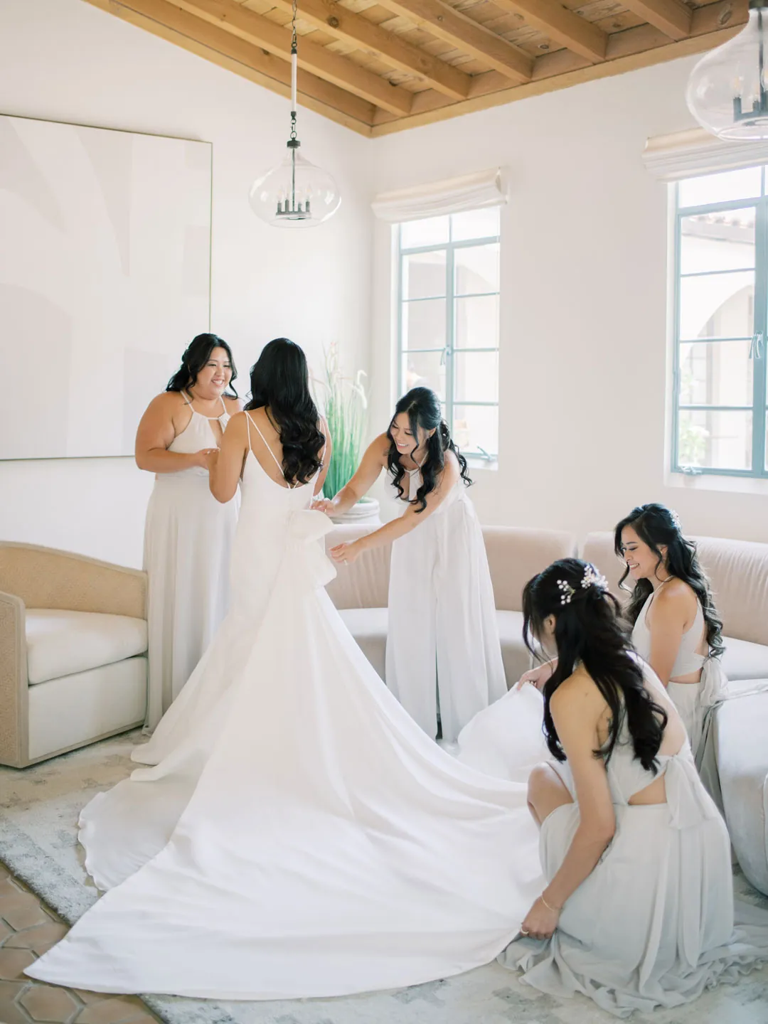 Friends arrange the bride’s gown in the dressing room.