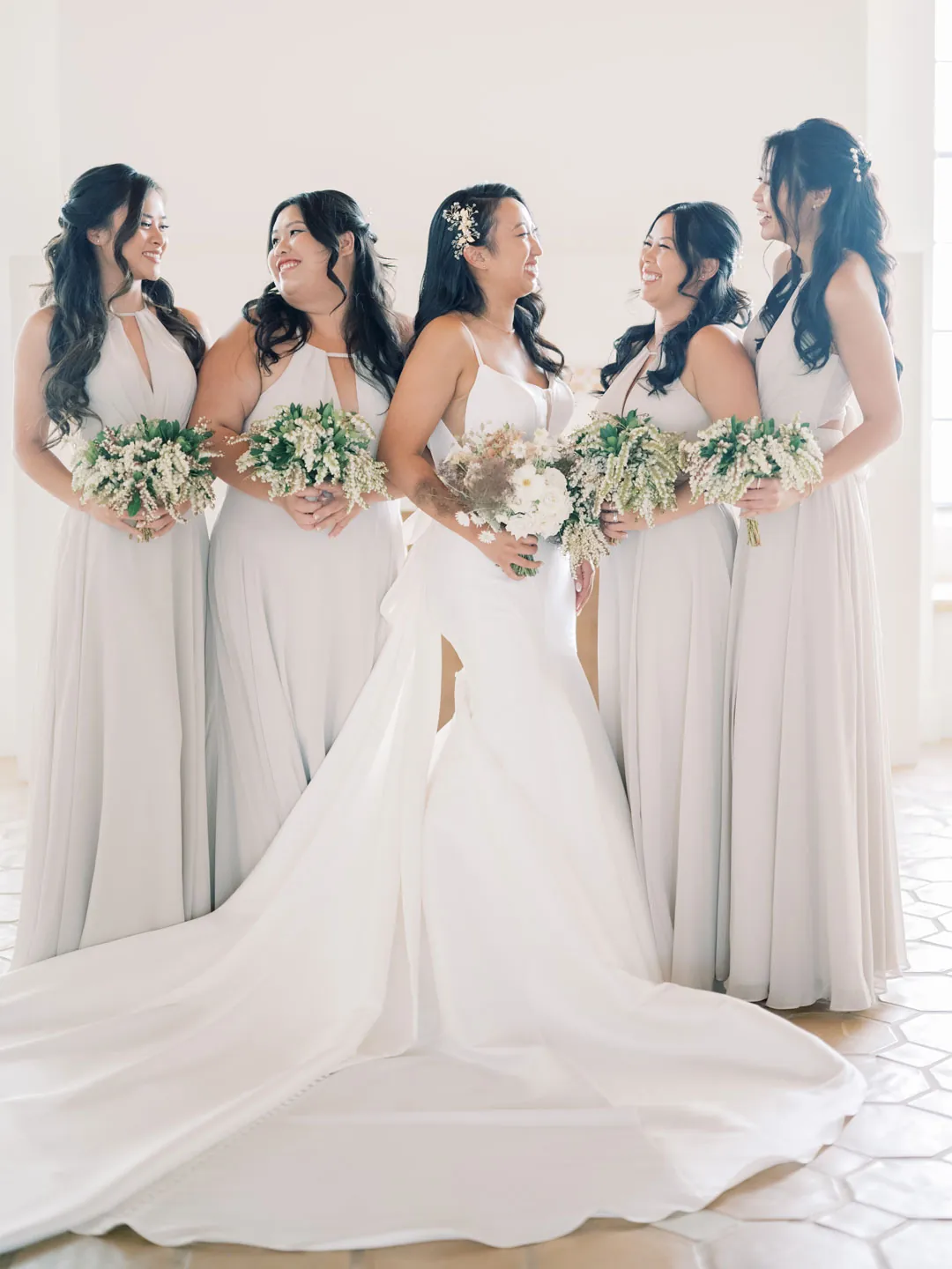 The bride and friends hold white and pink bouquets.