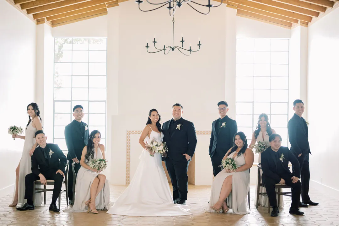 The wedding party poses beneath the covered courtyard ceiling.