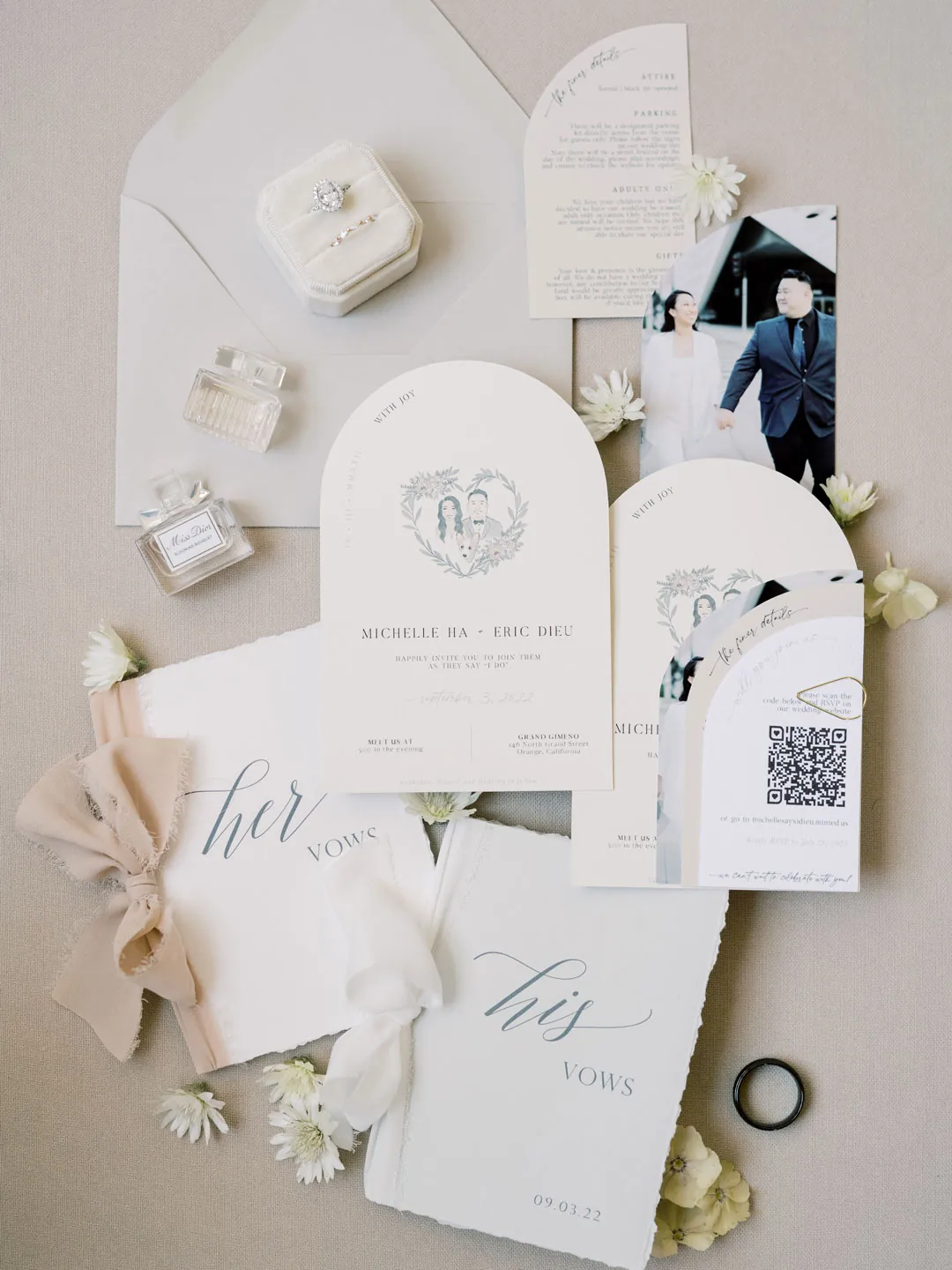 Wedding cards and accessories are arranged on white fabric.