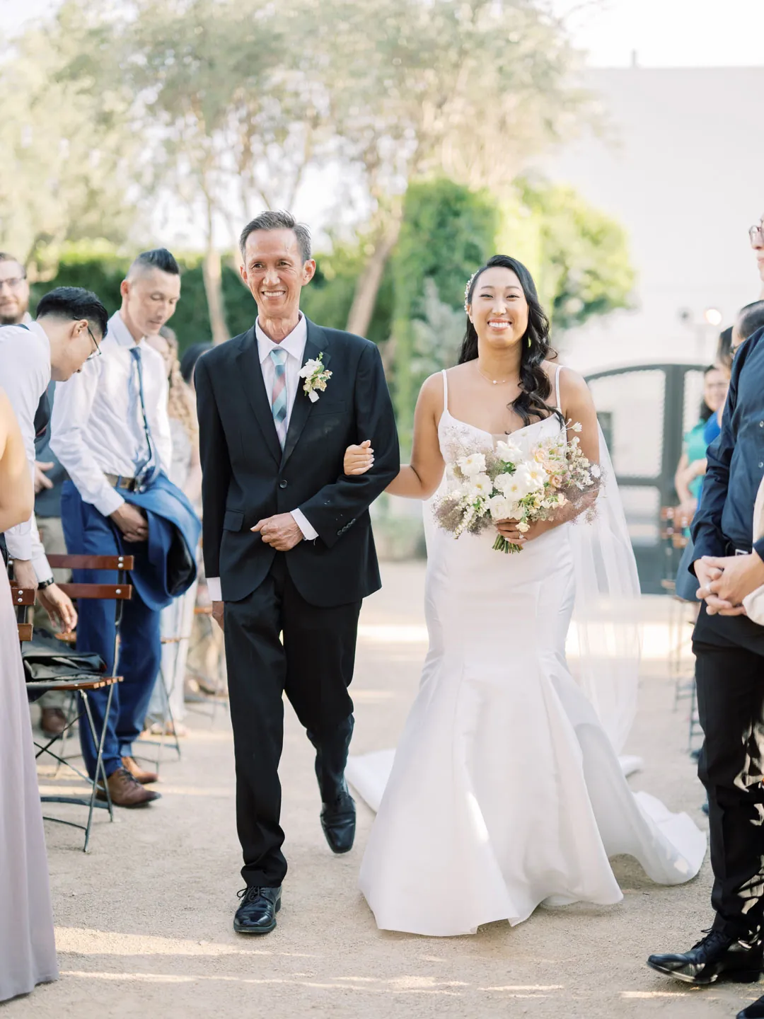 The bride walks down the aisle with an escort.