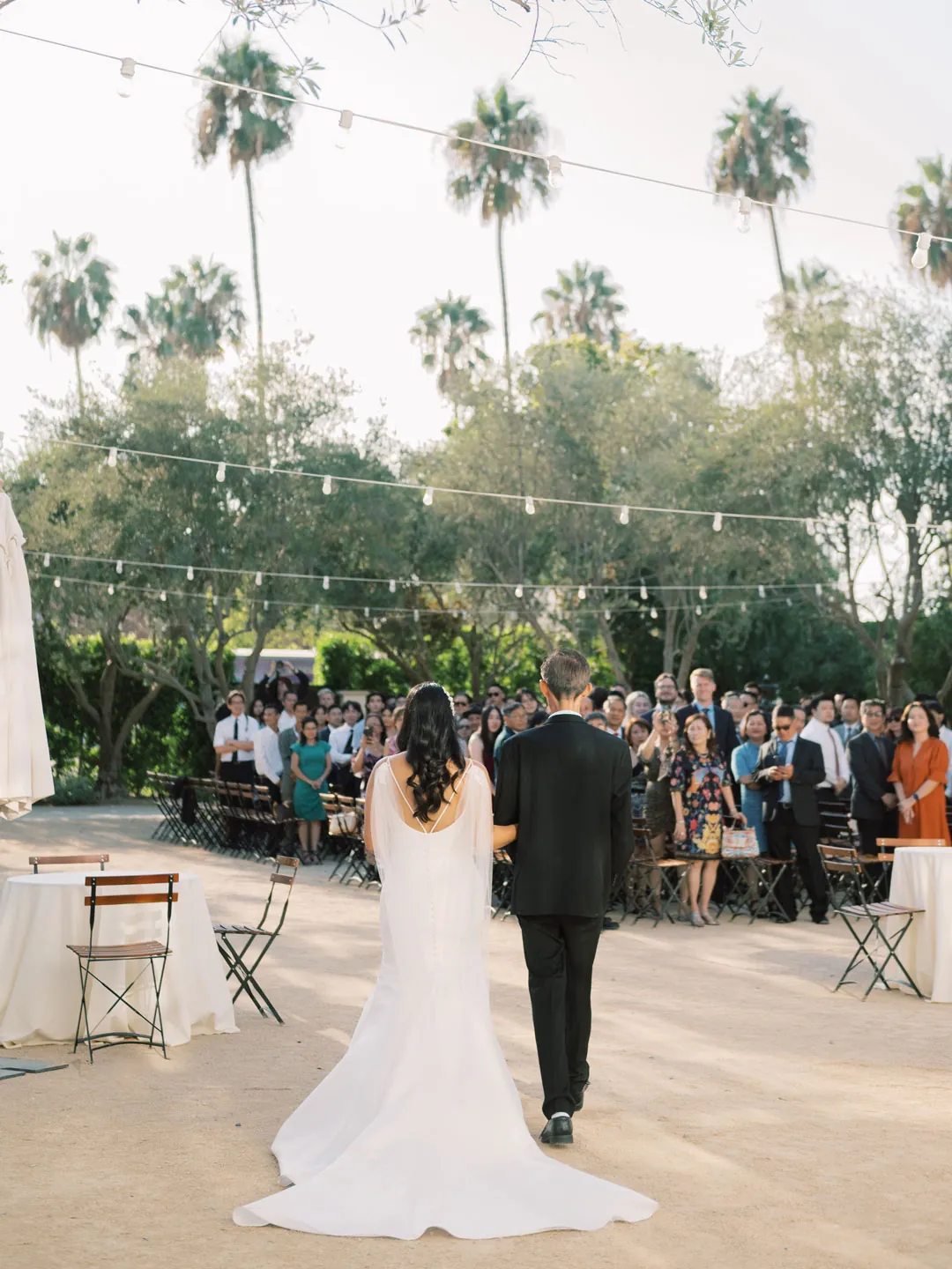 The groom approaches the outdoor ceremony through the courtyard.