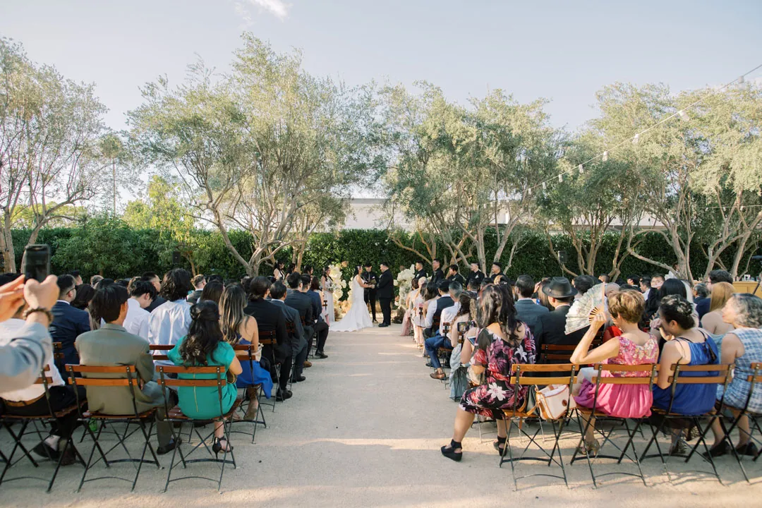 Guests seated along a courtyard wedding ceremony aisle