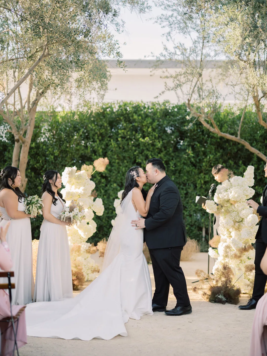 Bride and groom kissing between white floral arrangements