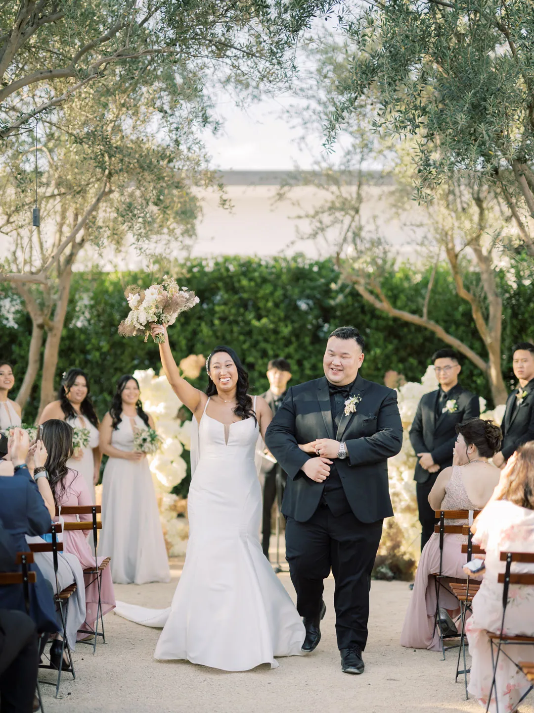 Bride raising her arm while walking down the aisle
