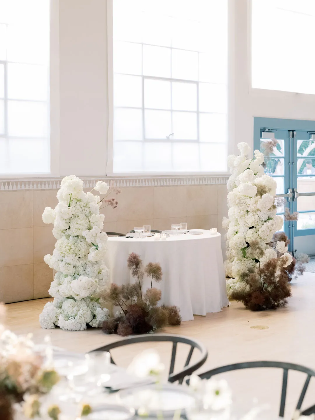 Sweetheart table framed by tall white floral arrangements