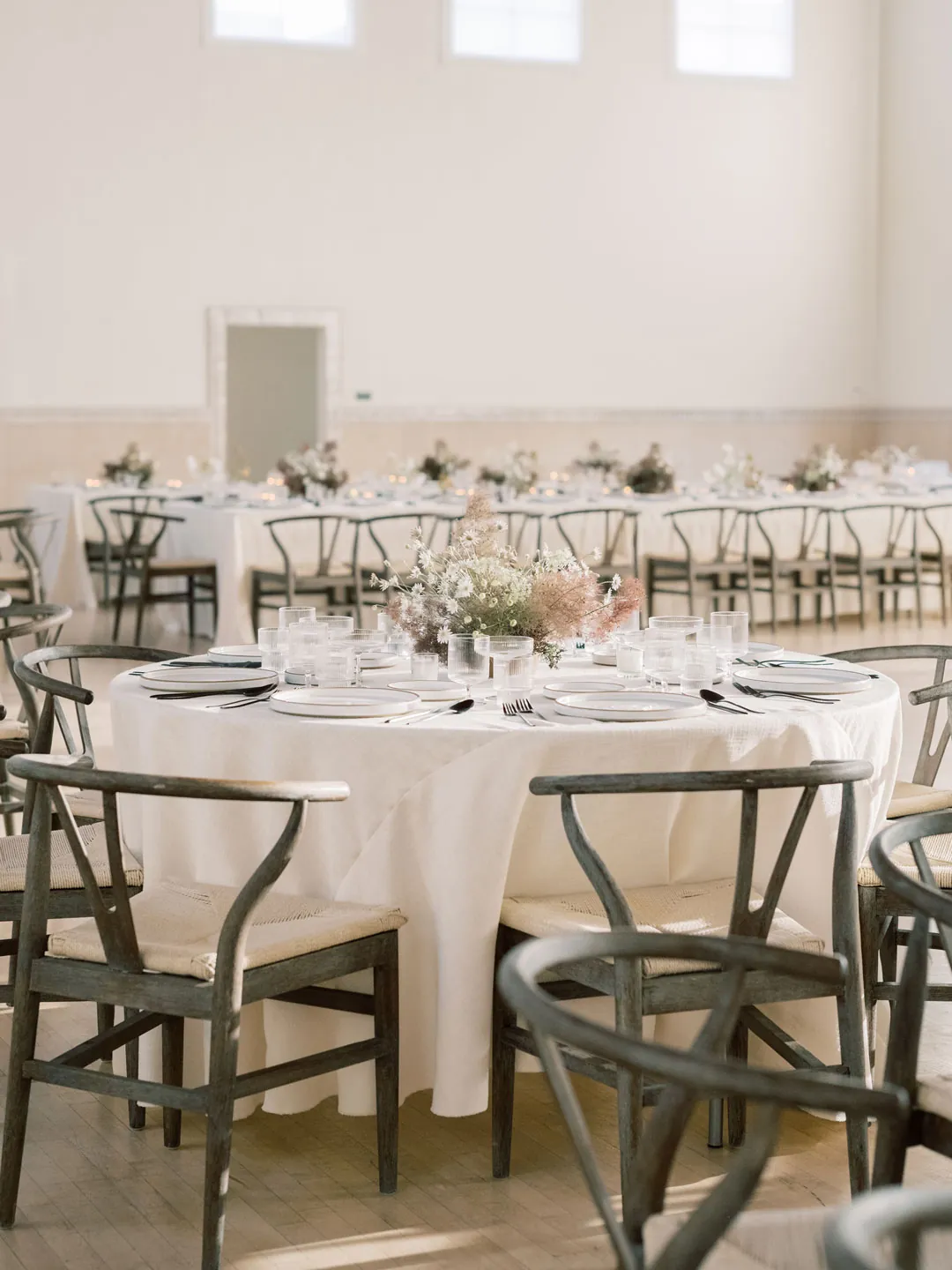 Round reception table with pale flowers and glassware