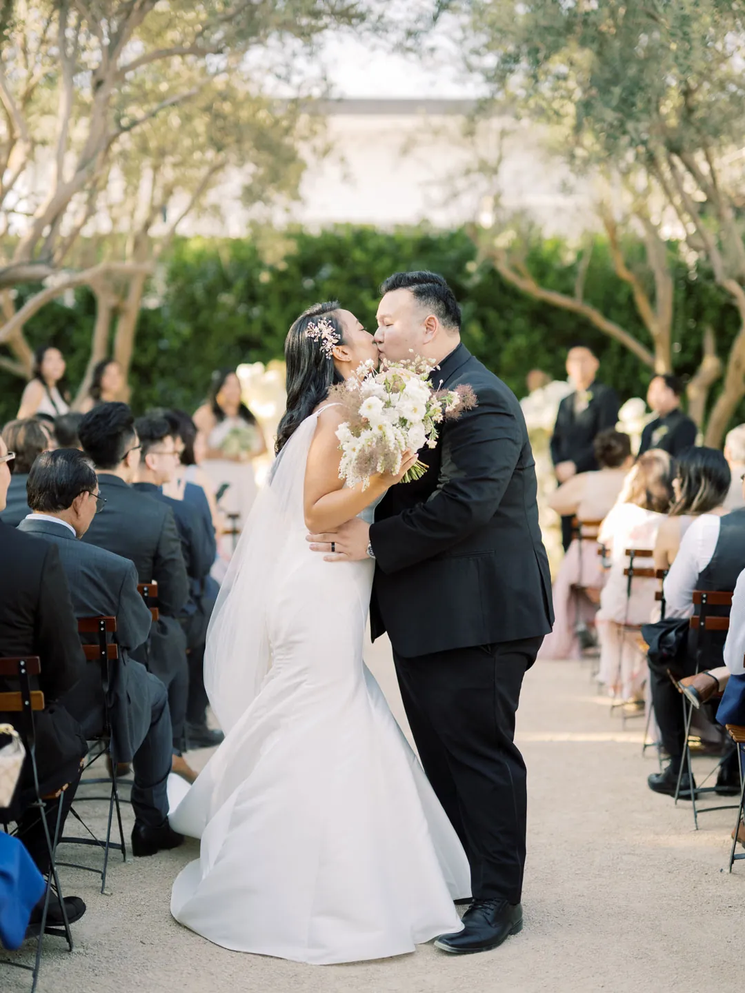 Newlyweds kissing among guests in the ceremony aisle