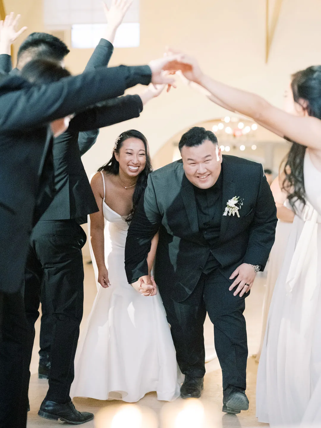 Newlyweds passing beneath guests' raised arms