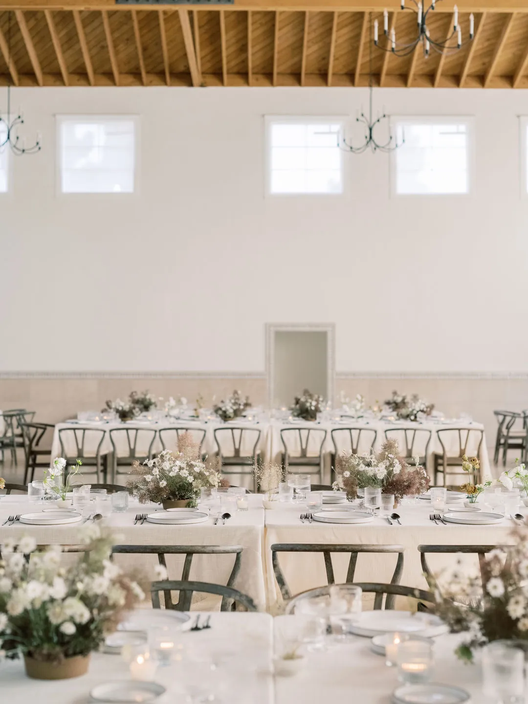 Reception hall arranged with dining tables beneath wood beams
