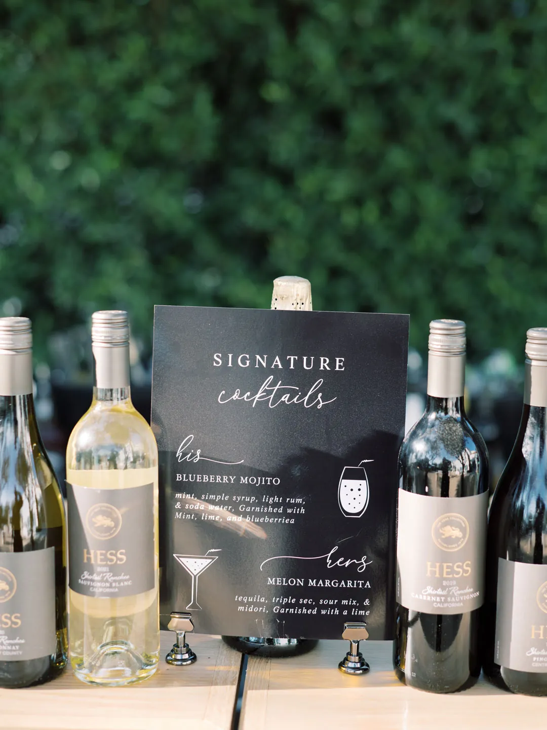 Signature cocktail menu displayed between wine bottles